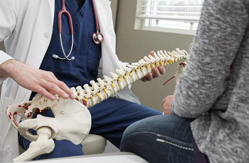 Doctor with spine model speaking to a patient